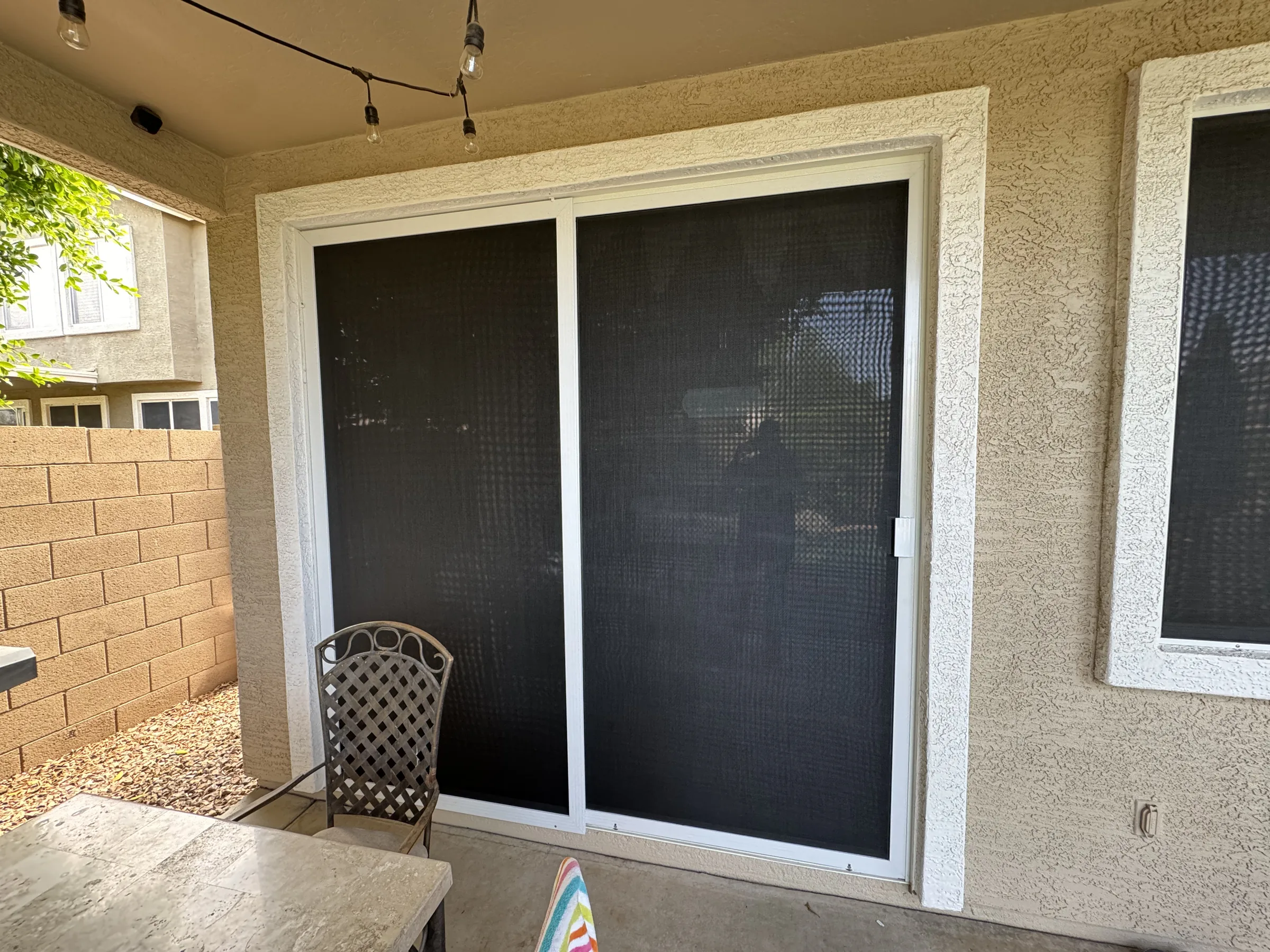 Covered patio with large sliding glass doors fitted with black retractable screens.
