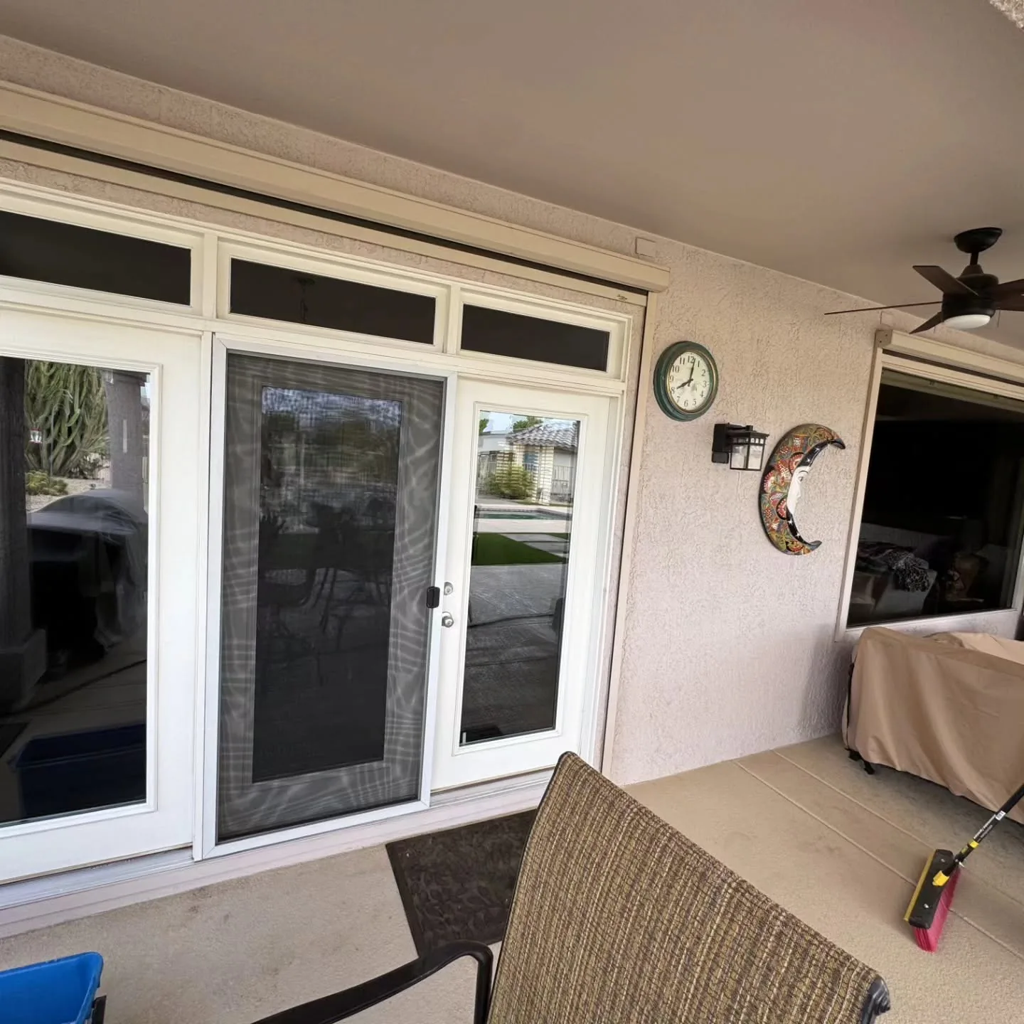 Covered patio with white-framed sliding glass doors fitted with black retractable screens.