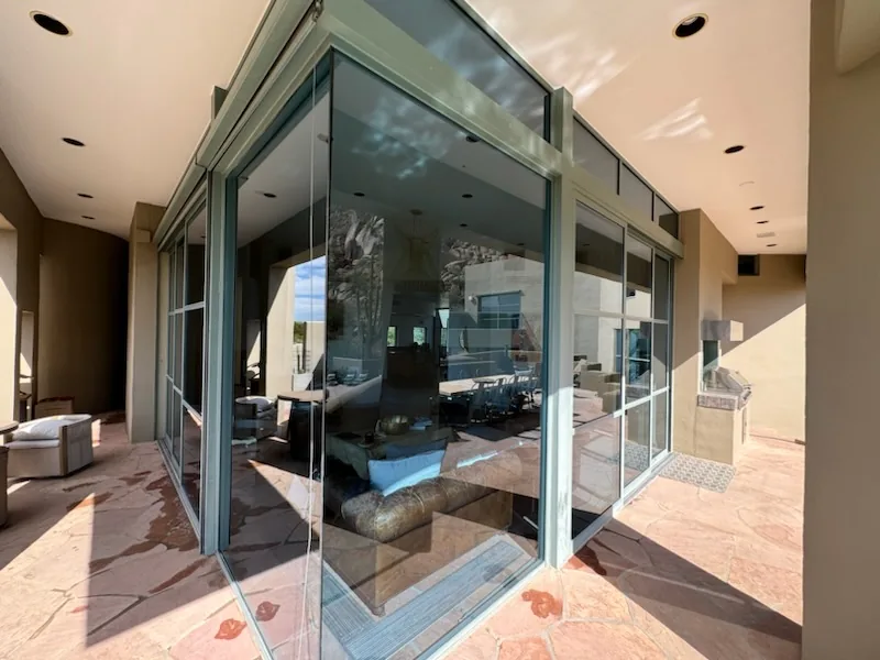 Large glass sliding doors and windows with gray aluminum frames in a modern home interior.